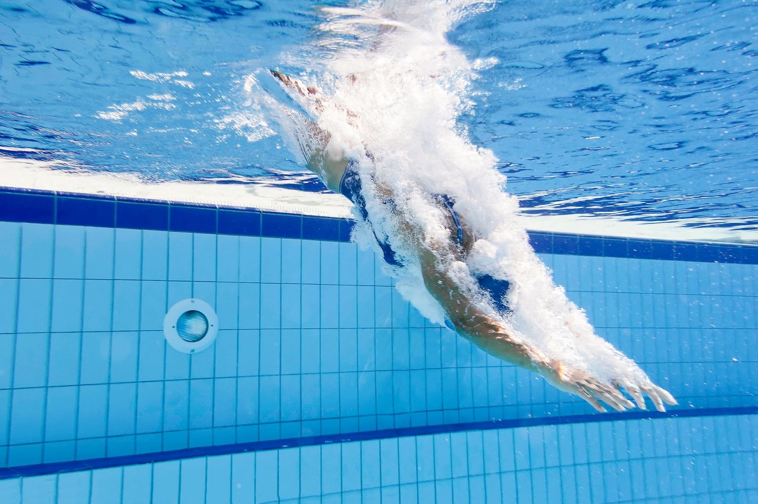 Ein Schwimmer im Pool, der grade ins Wasser eintaucht.